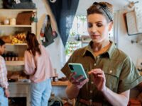 Woman uses mobile phone in small retail business.